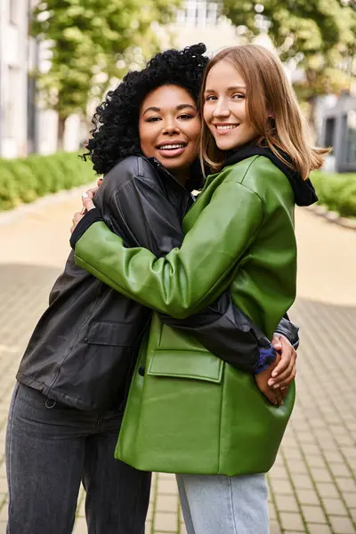 Two attractive diverse women warmly hugging on a sidewalk. — Stock Photo