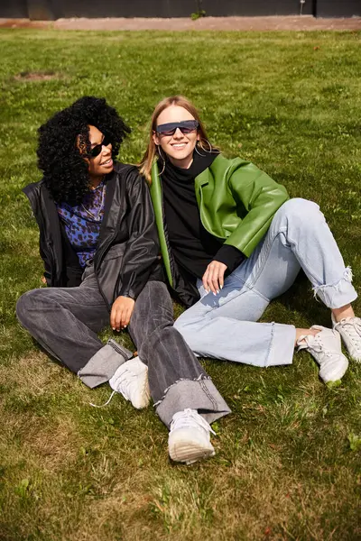 Duas mulheres em trajes aconchegantes sentadas na grama, desfrutando de um momento sereno ao ar livre. — Fotografia de Stock