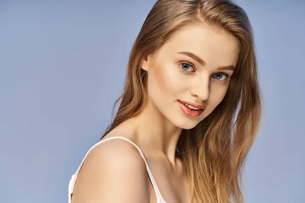 Une jeune femme blonde aux cheveux longs pose dans un décor studio, exsudant une beauté captivante et éthérée. — Photo de stock