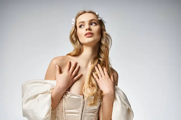 Eine junge, blonde Frau posiert elegant in einem weißen Kleid in einem Studio für ein atemberaubendes Porträt. — Stockfoto
