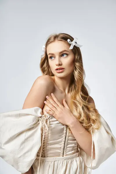 Молода блондинка з бантом у волоссі випромінює красу і елегантність у білій сукні. — стокове фото