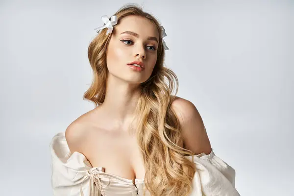 Uma jovem, bela mulher loira graciosamente posa em um vestido branco fluindo em um estúdio. — Fotografia de Stock