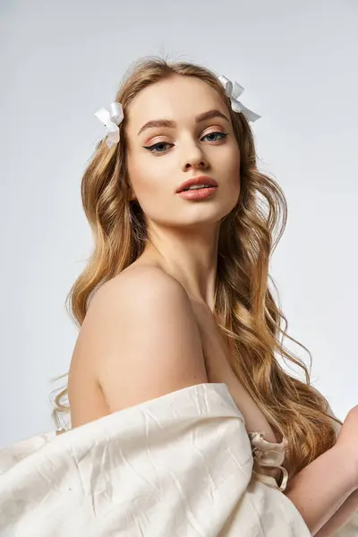 Une jeune femme blonde respire la grâce dans une robe blanche fluide, mettant en valeur ses longs cheveux dans un cadre de studio. — Photo de stock