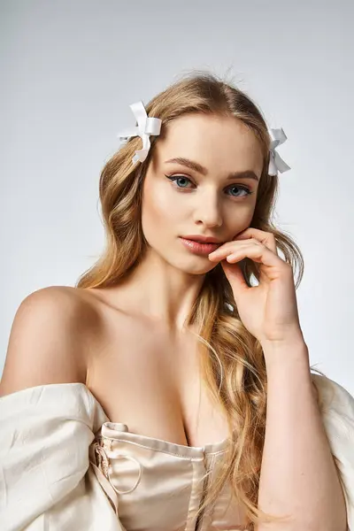 Une jeune femme blonde respire la tranquillité avec un arc blanc ornant gracieusement ses cheveux dans un décor de studio. — Photo de stock