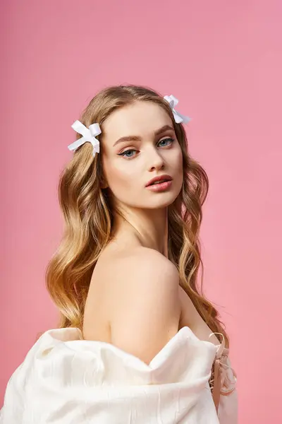 Une jeune femme blonde portant une robe blanche avec deux nœuds dans les cheveux, posant élégamment dans un décor de studio. — Photo de stock