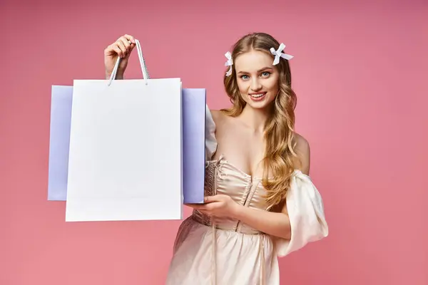 A stunning young woman with blonde hair joyfully holds a shopping bag in a studio setting. — Stock Photo