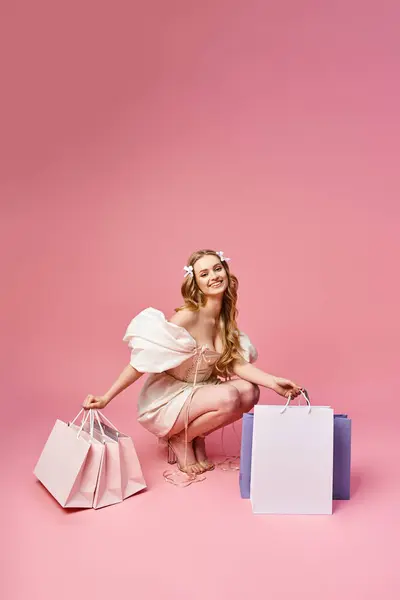 Uma jovem mulher loira bonita se ajoelha elegantemente no chão cercado por sacos de compras. — Fotografia de Stock