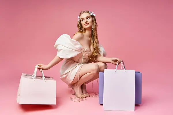 A young blonde woman sits on the ground holding two bags in a studio setting. — Stock Photo