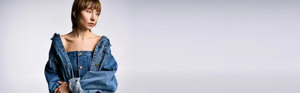 A young woman with short hair stands confidently, posing for a picture in a chic denim dress in a studio setting. — Stock Photo