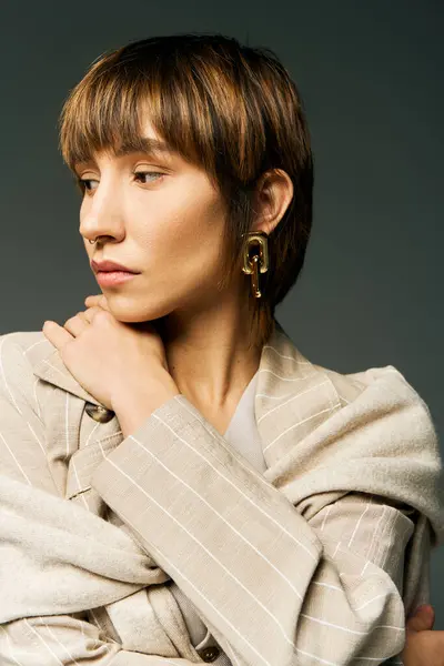 Eine stylische junge Frau mit kurzen Haaren posiert selbstbewusst in einem trendigen Mantel in einem Studio-Setting. — Stockfoto