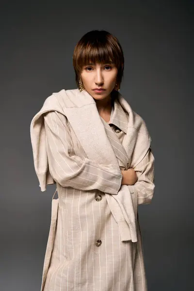 A stylish young woman with short hair strikes a confident pose in a trench coat, exuding elegance and sophistication. — Stock Photo
