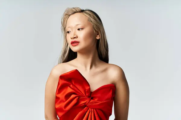 Lebendige Asiatin in rotem Kleid und selbstbewusster Pose. — Stockfoto