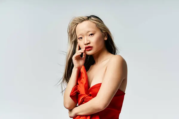 A captivating Asian woman gracefully poses in a vibrant red dress. — Stock Photo
