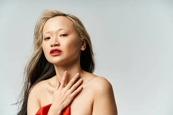 Asian woman in red dress, hands on chest. - foto de stock