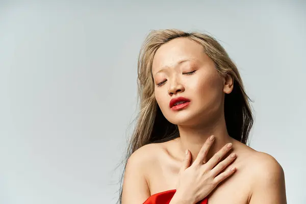 An attractive Asian woman in a vibrant red dress, eyes closed in a serene pose. — Stock Photo