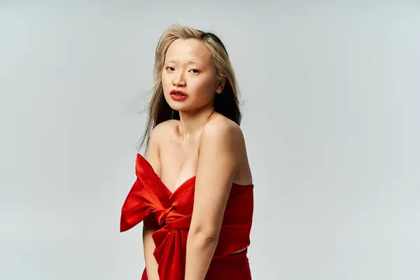 Une jolie femme asiatique dans une robe rouge vibrante frappant une pose pour une image. — Photo de stock