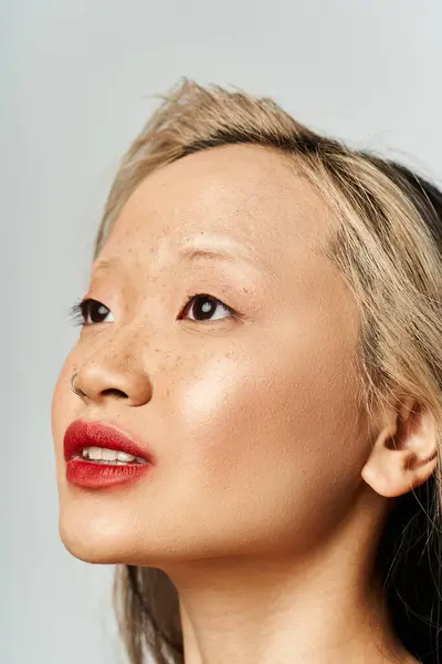 Elegant Asian woman in vibrant attire gazes upward, red lipstick enhancing her captivating allure. — Stock Photo