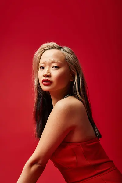 Uma mulher asiática cativante faz uma pose em um vestido vermelho vibrante. — Fotografia de Stock
