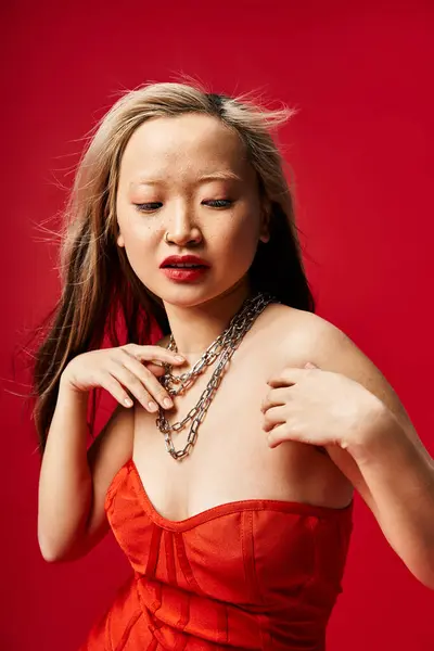 A captivating Asian woman in a vibrant red dress strikes a graceful pose for a photo. — Stock Photo