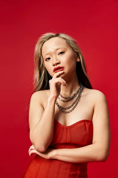 Стильная азиатка, ставящая позу в ярком красном платье. — стоковое фото