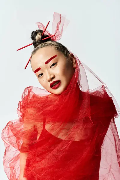 An attractive Asian woman in a red dress strikes a powerful pose with a veil on her head. — Stock Photo