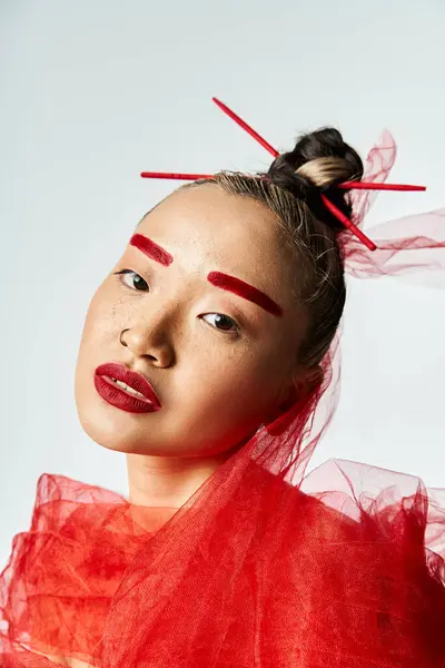 Asiatin im roten Kleid posiert mit Stöcken, die aus ihrem Gesicht ragen. — Stockfoto