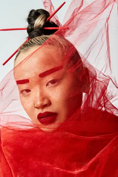 Mujer asiática exuda encanto con maquillaje rojo y un velo cubierto. - foto de stock