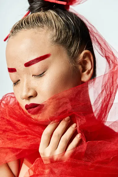 Mulher asiática com maquiagem vermelha ousada e um véu de cabeça posando elegantemente. — Fotografia de Stock
