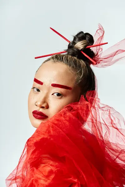 Femme asiatique en robe rouge avec des bâtons rouges ornement dans les poses de cheveux gracieusement. — Photo de stock