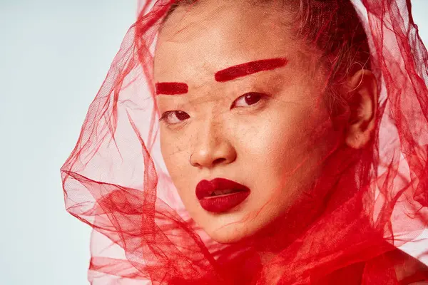 Asian woman with red makeup and veil posing gracefully. — Stock Photo