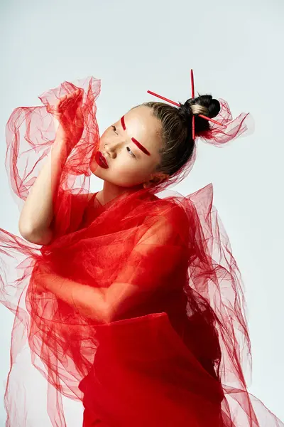 Mujer asiática en vestido rojo, velo alrededor del cuello, golpeando una pose. - foto de stock