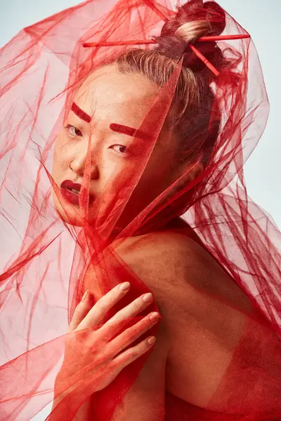 Азіатська жінка в яскравому одязі, вуаль витончено прикриває голову. — стокове фото