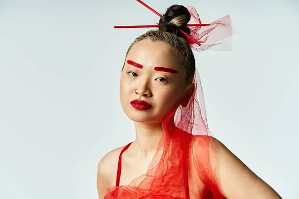 Una donna asiatica attraente con un trucco rosso vibrante e un velo sulla testa posa con grazia. — Foto stock