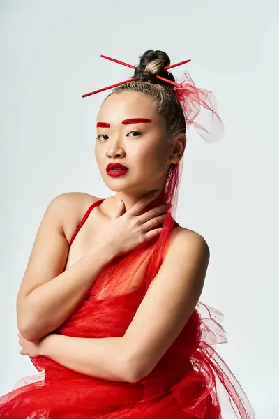 Une jolie femme asiatique dans une robe rouge pose élégamment avec un voile sur la tête. — Photo de stock