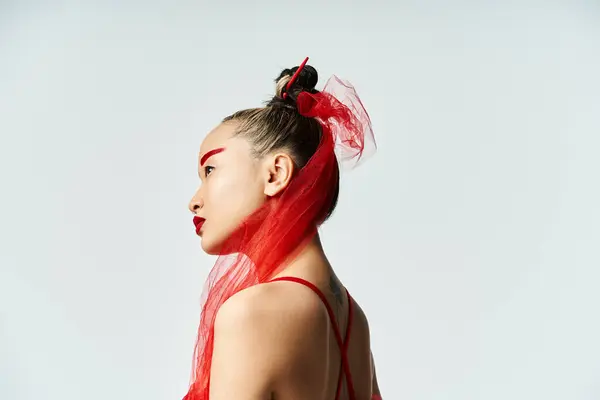 An attractive Asian woman poses gracefully wearing a striking red veil. — Stock Photo