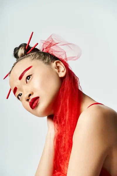 Очаровательная азиатка с красным макияжем и волосами ярко позирует. — стоковое фото