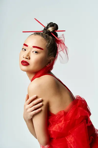 An attractive Asian woman captivating in a flowing red dress with matching red makeup. — Stock Photo