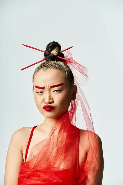 Une femme asiatique vibrante pose dans une robe rouge avec un voile sur la tête. — Photo de stock