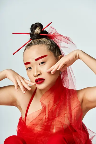 A captivating Asian woman in a vibrant red dress, hands on head. — Stock Photo