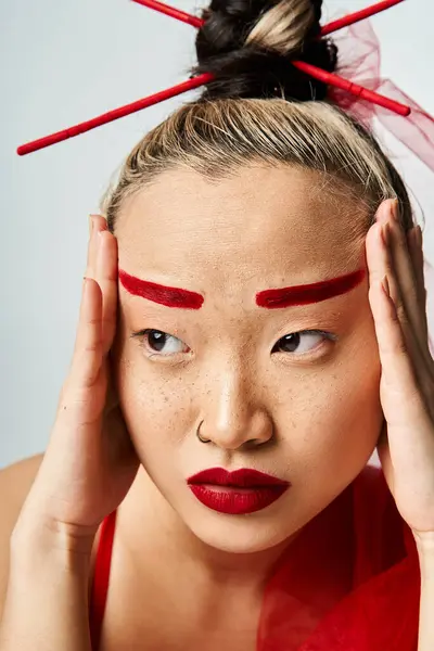 Uma mulher asiática atraente com maquiagem vermelha segurando sua cabeça dramaticamente. — Fotografia de Stock