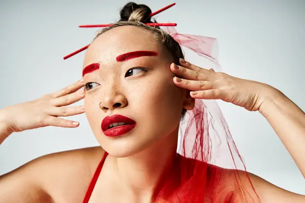 Asiatin mit auffallend rotem Make-up trägt einen Schleier, der Eleganz und Mysterium ausstrahlt. — Stockfoto
