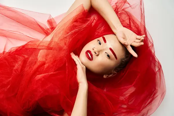 Asian woman in red dress striking a bold pose with hands on head. — Stock Photo