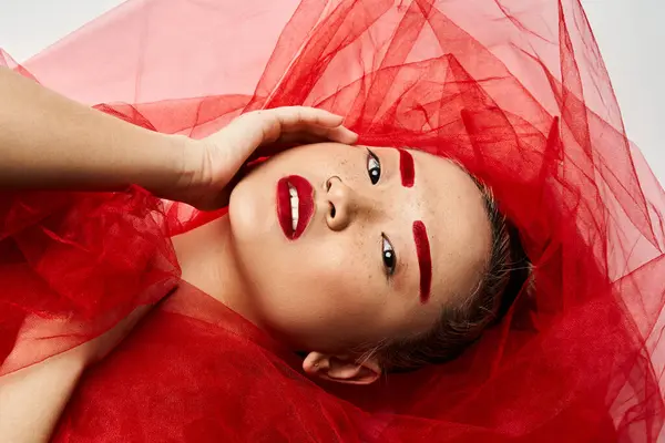 A vibrant Asian woman poses in a striking red dress and matching makeup. — Stock Photo