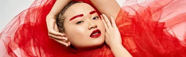 Active Asian woman in vibrant red dress, hands resting on head. — Stock Photo