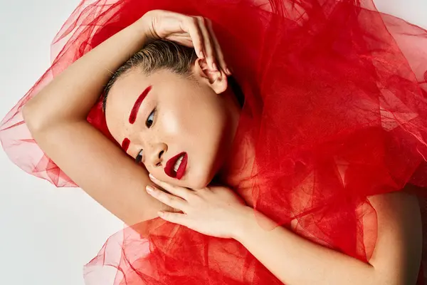 Donna asiatica in abito rosso con le mani sulla testa, colpisce una posa drammatica. — Foto stock