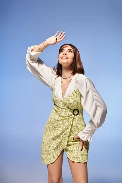 Uma jovem mulher com cabelo morena faz uma pose em um vestido curto elegante, exalando graça e elegância em um ambiente de estúdio. — Fotografia de Stock