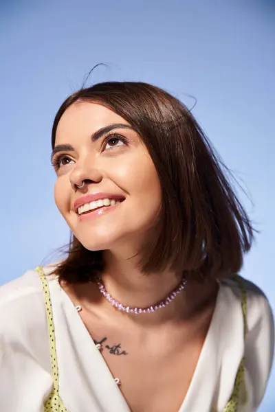 Eine junge Frau mit brünetten Haaren strahlt in einem weißen Hemd und einer klassischen Perlenkette im Studio Anmut aus. — Stockfoto