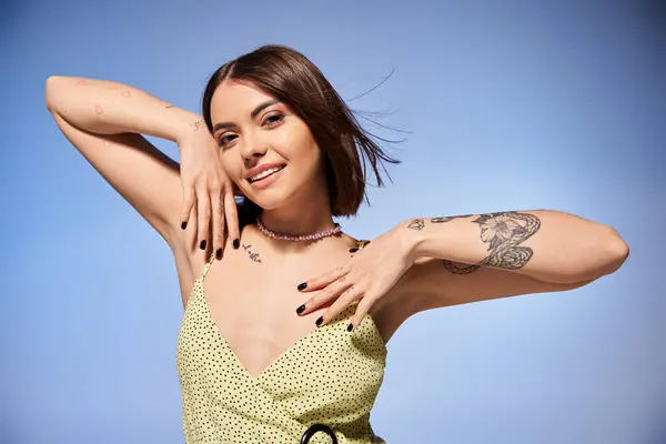 Молодая женщина с брюнетками уверенно позирует для фотографии, демонстрируя поразительную татуировку на руке. — стоковое фото
