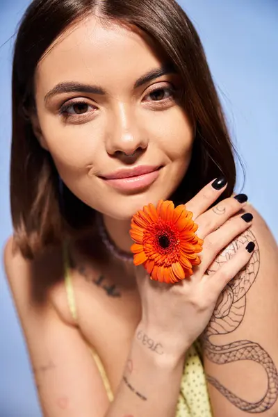 A young woman with brunette hair holding a vibrant flower in her hand, showcasing natural beauty and grace. — Stock Photo
