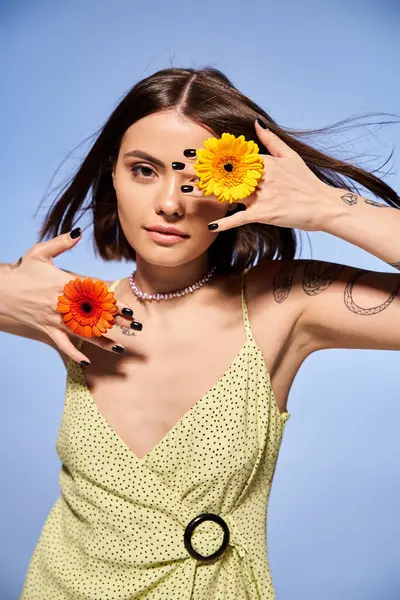 A young brunette woman gracefully holds a delicate flower in her hand, exuding a sense of beauty and connection to nature. — Stock Photo